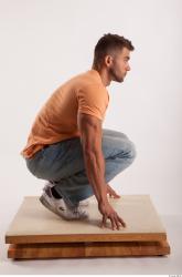 Kneeling pose orange thsirt light blue jeans of bodybuilder Harold